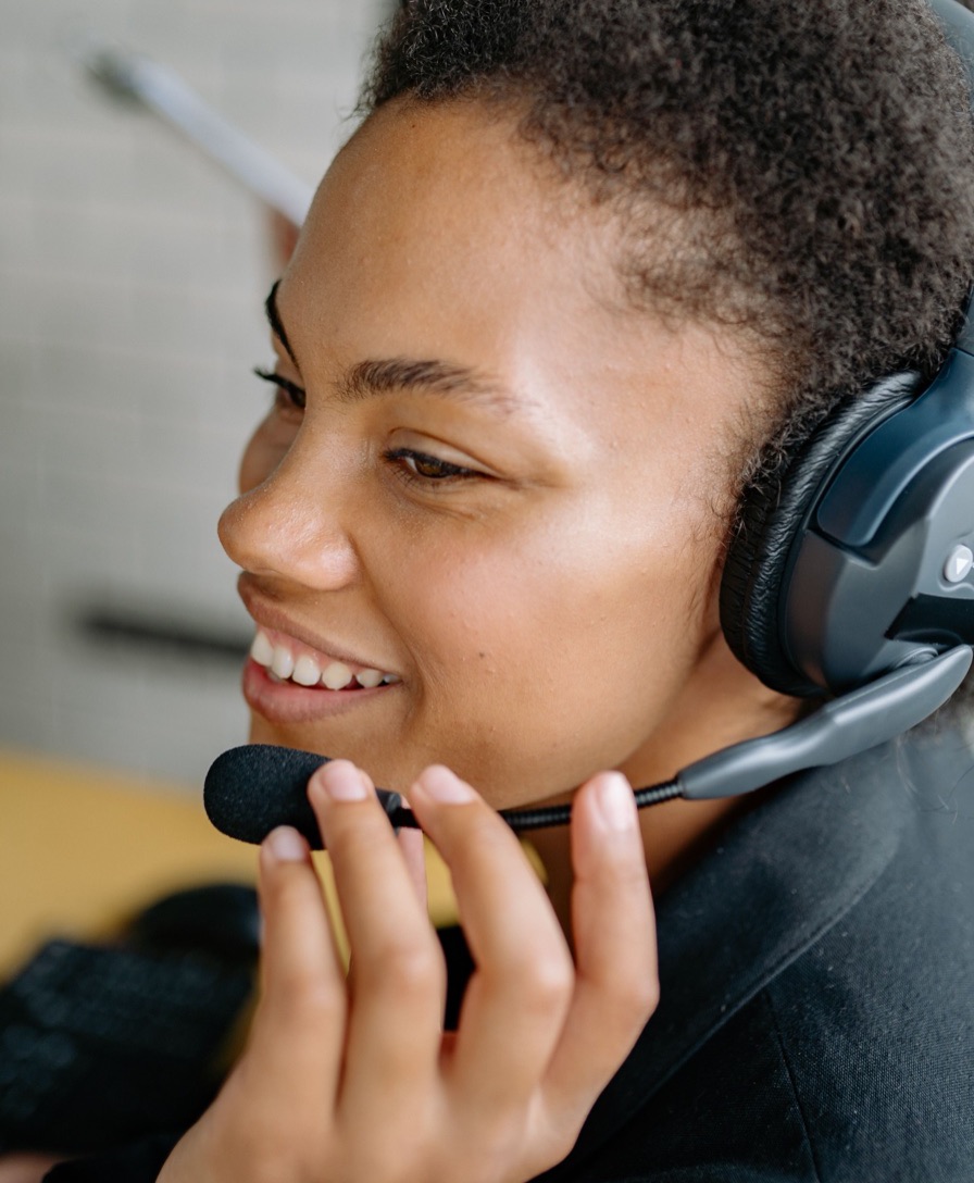 Imagem ilustrativa: atendente com headset sorri segurando o microfone
