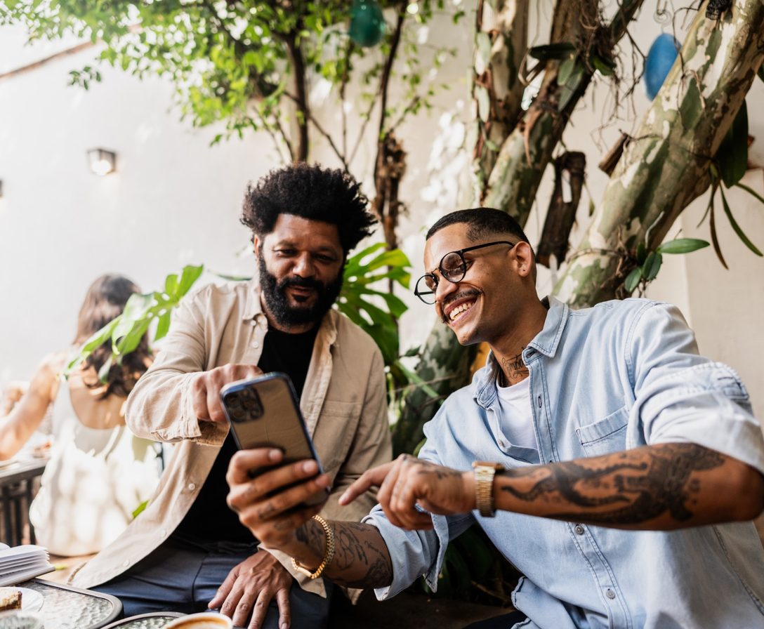 Imagem ilustrativa: duas pessoas sorriem olhando o celular juntas