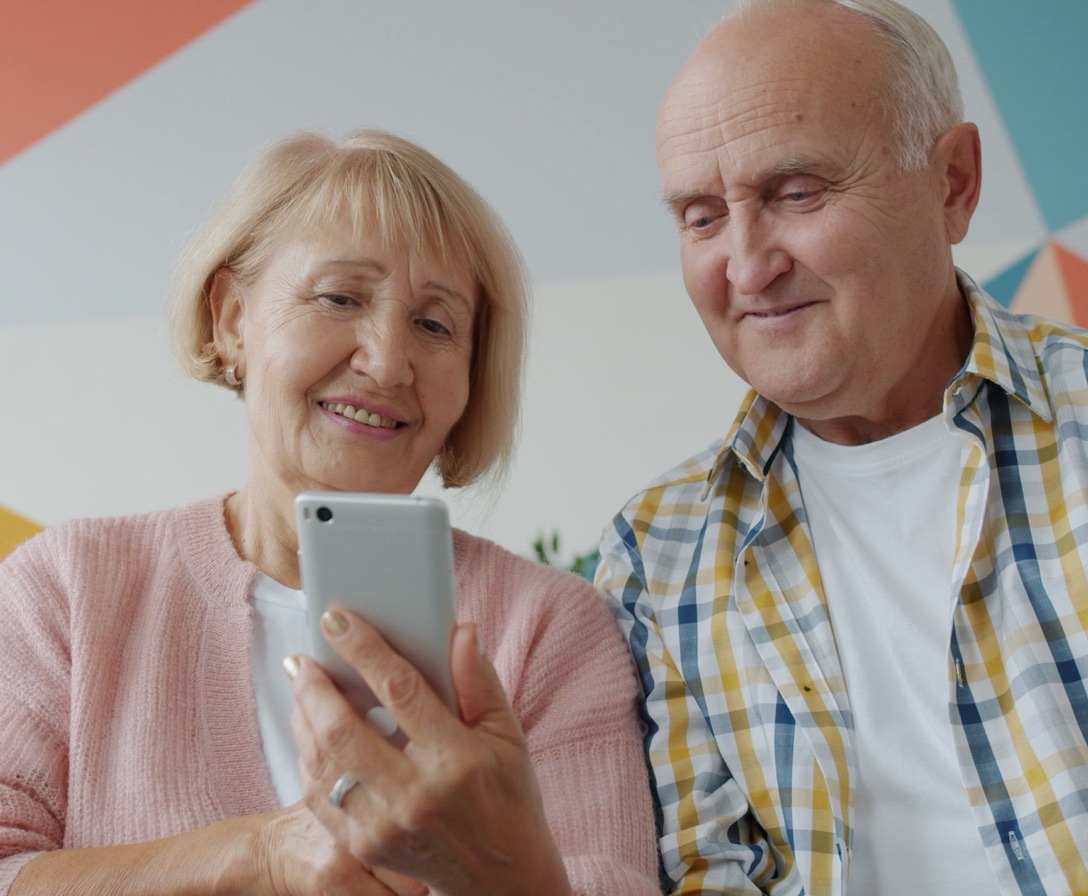 Imagem ilustrativa: casal sorri olhando o celular juntos